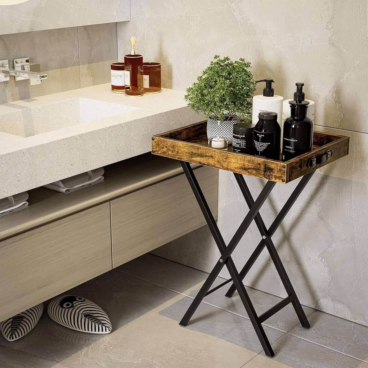 Rustic Brown folding TV tray table used as a bathroom organizer next to a vanity. Featuring a waterproof wooden tray top with black metal legs holding towels and toiletries.